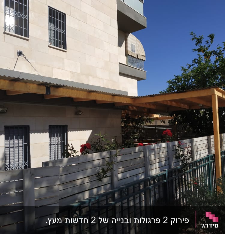 פרגולה מעץ ליד גדר עץ בגינה